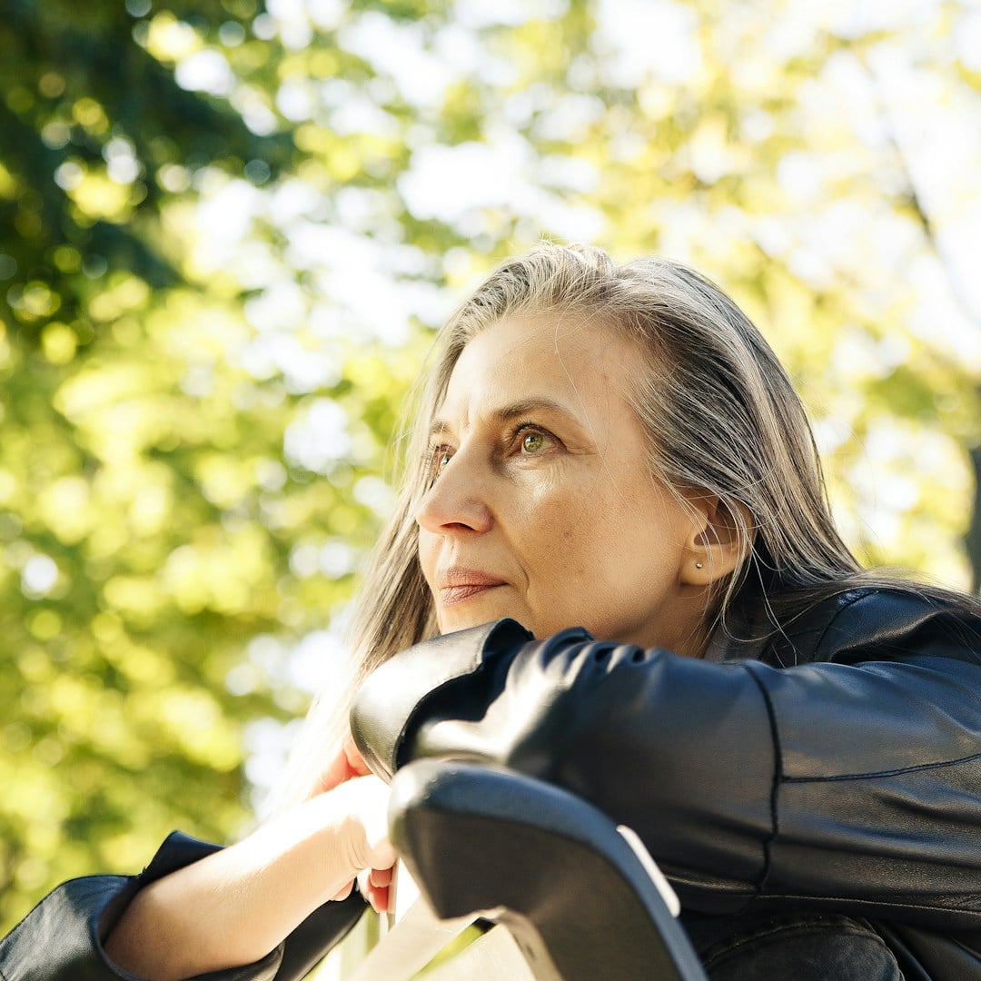 Older woman with grey hair looking thoughtfully into the distance in warm light